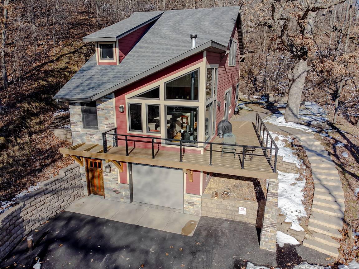A modern small house with large glass windows set above a garage on a rocky hillside