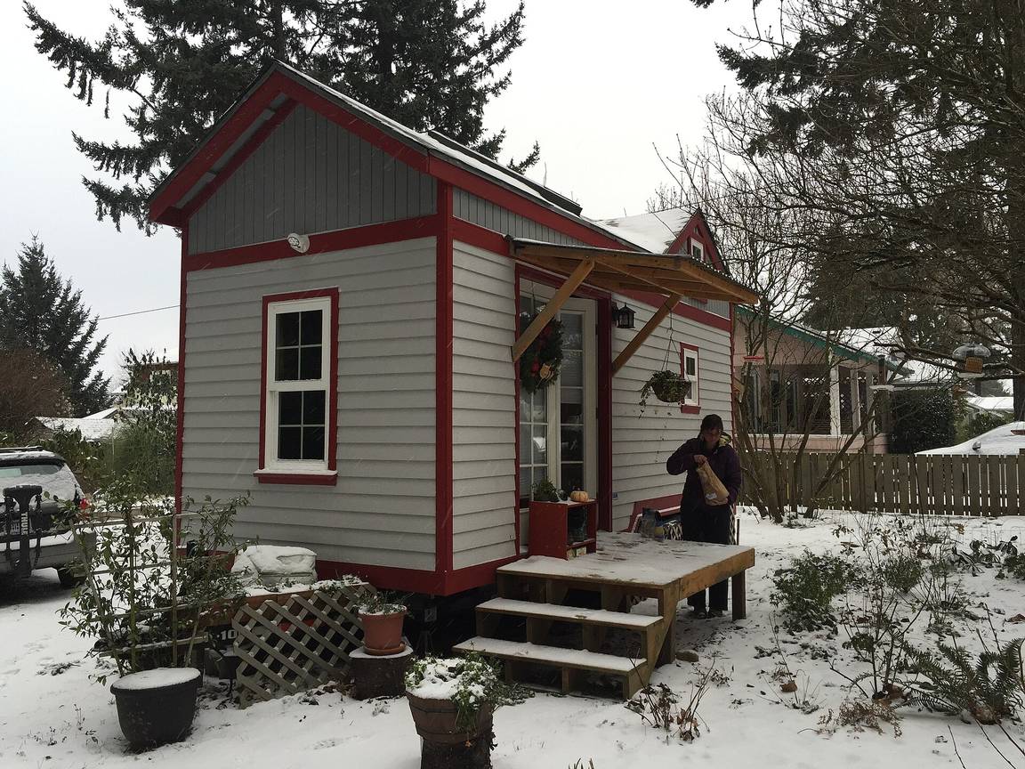 A small house in Portland, Oregon, under snow, with a deep porch and a mature tree in front