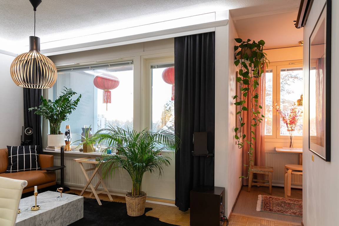 A bright studio apartment interior with a combined living and sleeping space, kitchen and large windows