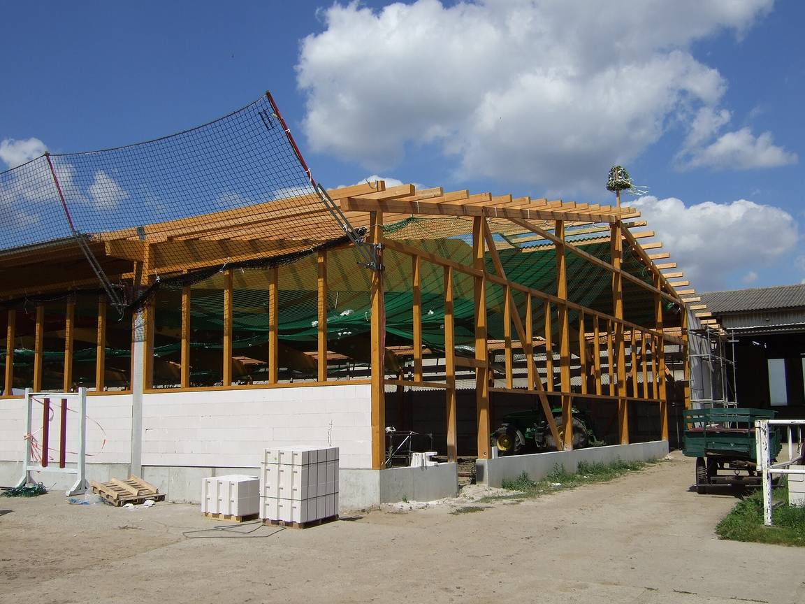 Timber frame of a house under construction, showing posts, beams and roof structure before cladding