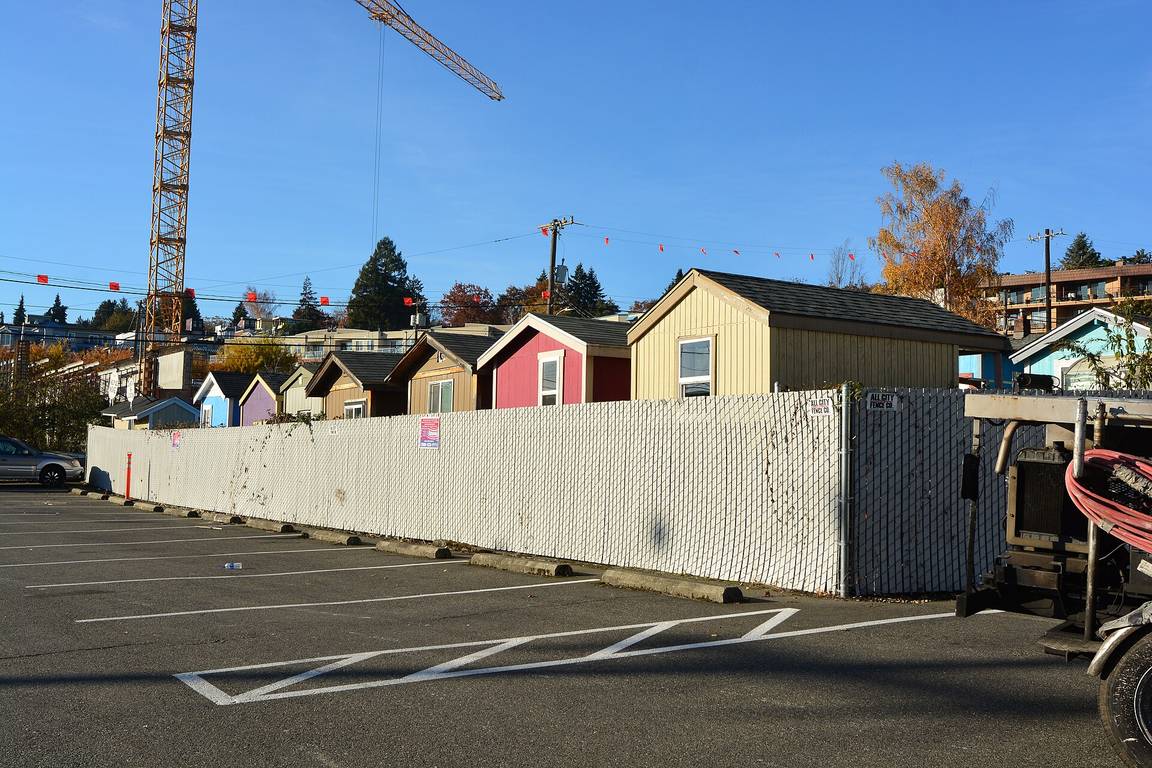 A tiny house village in Seattle with rows of small colourful houses behind a fence