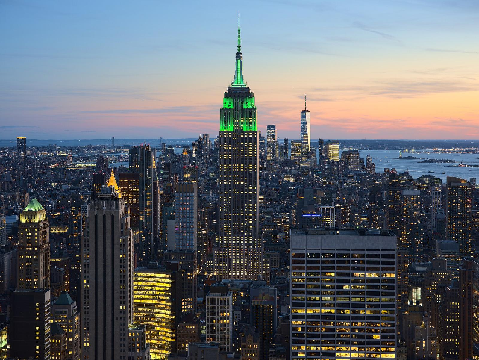 The Empire State Building floodlit at dusk above the Manhattan skyline