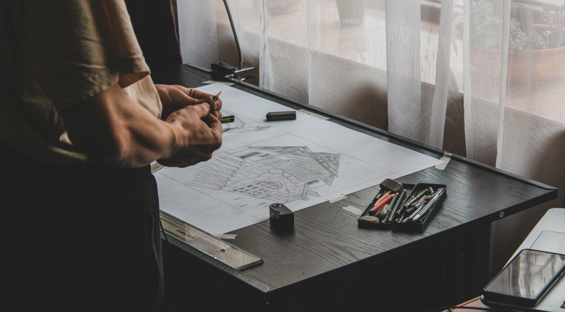 Architect developing a building drawing by hand at a drafting table
