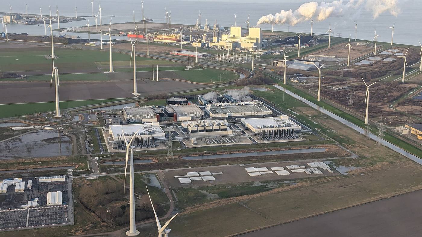 Data-centre campus at Eemshaven surrounded by wind turbines at dusk
