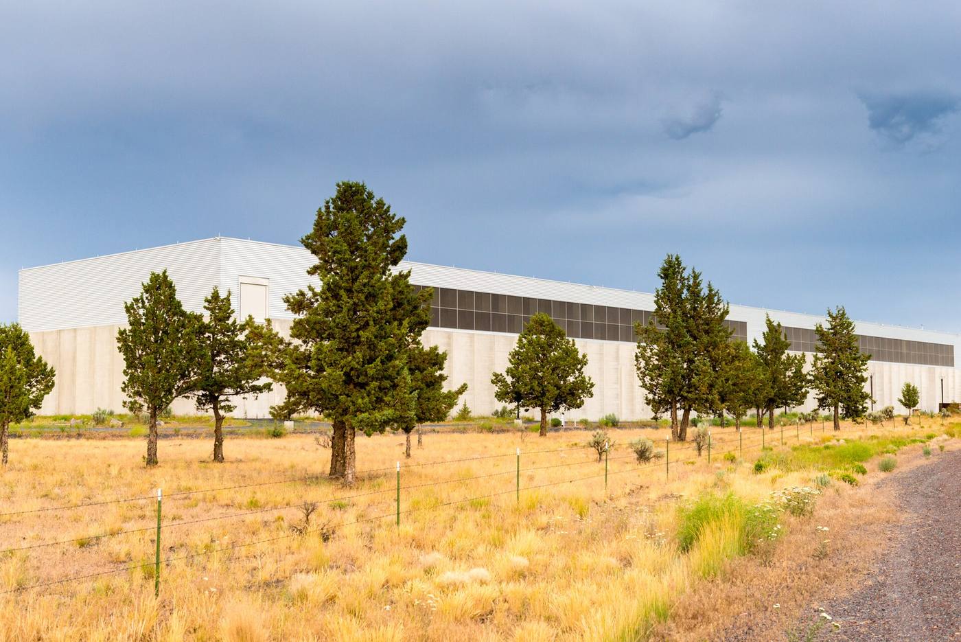 A vast windowless concrete data-centre hall stretching beside a highway
