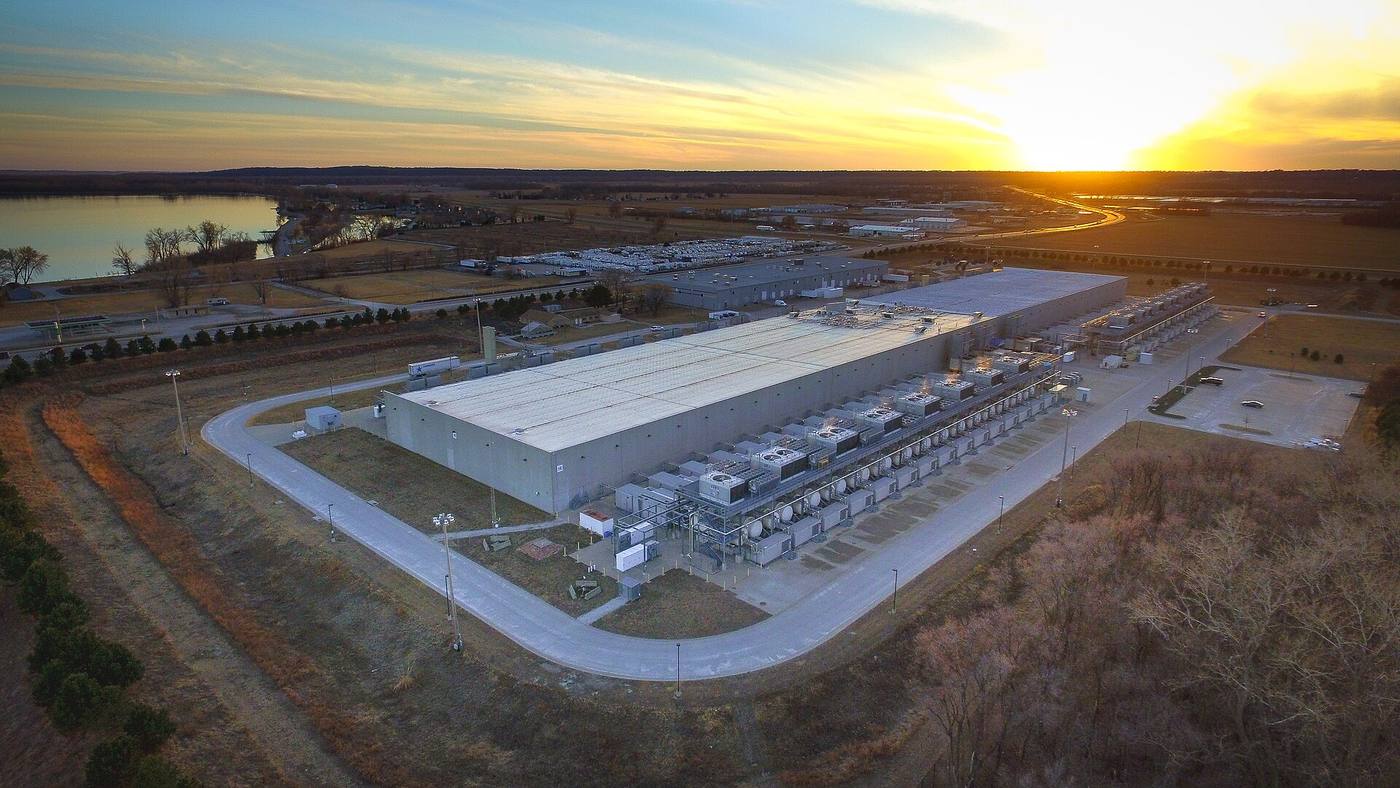 Aerial view of a large data-centre campus with cooling plants at sunset