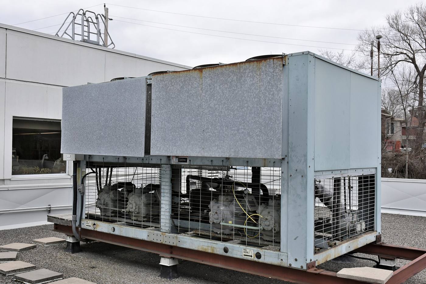 An air-cooled liquid chiller unit mounted on a gravel industrial roof