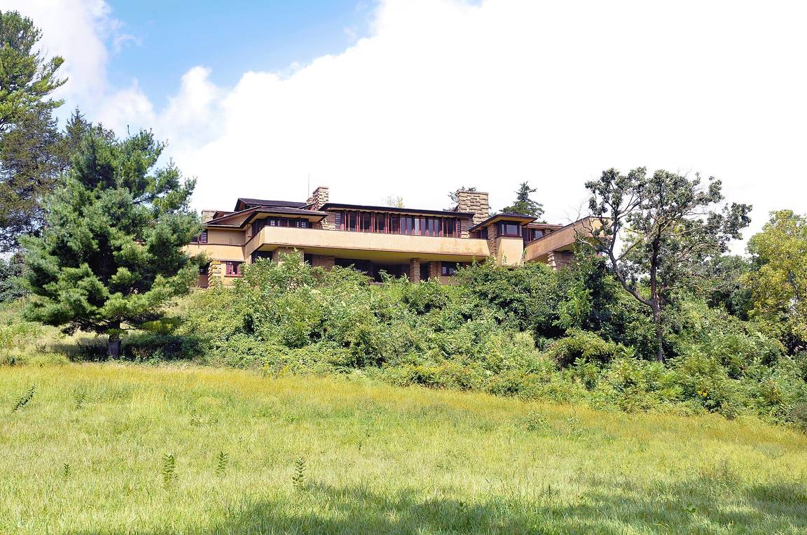 Taliesin in Wisconsin, low stone and plaster wings wrapping around the brow of a green hill