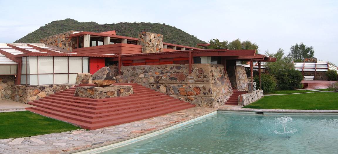 Taliesin West in the Arizona desert, with rugged stone walls, canvas roofs and mountains behind