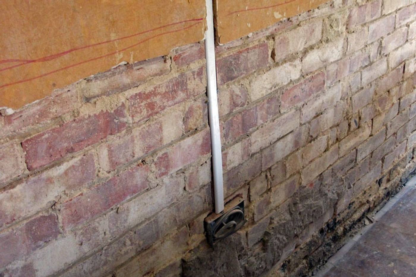 Plaster removed to expose rising damp in masonry — diagnosis before treatment