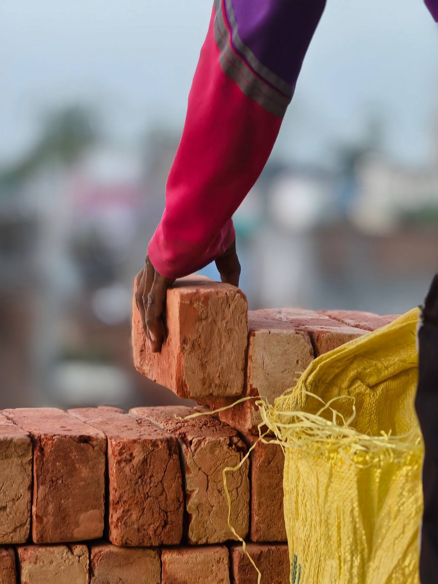 Close-up of a worker's hand placing a brick on a wall at a construction site