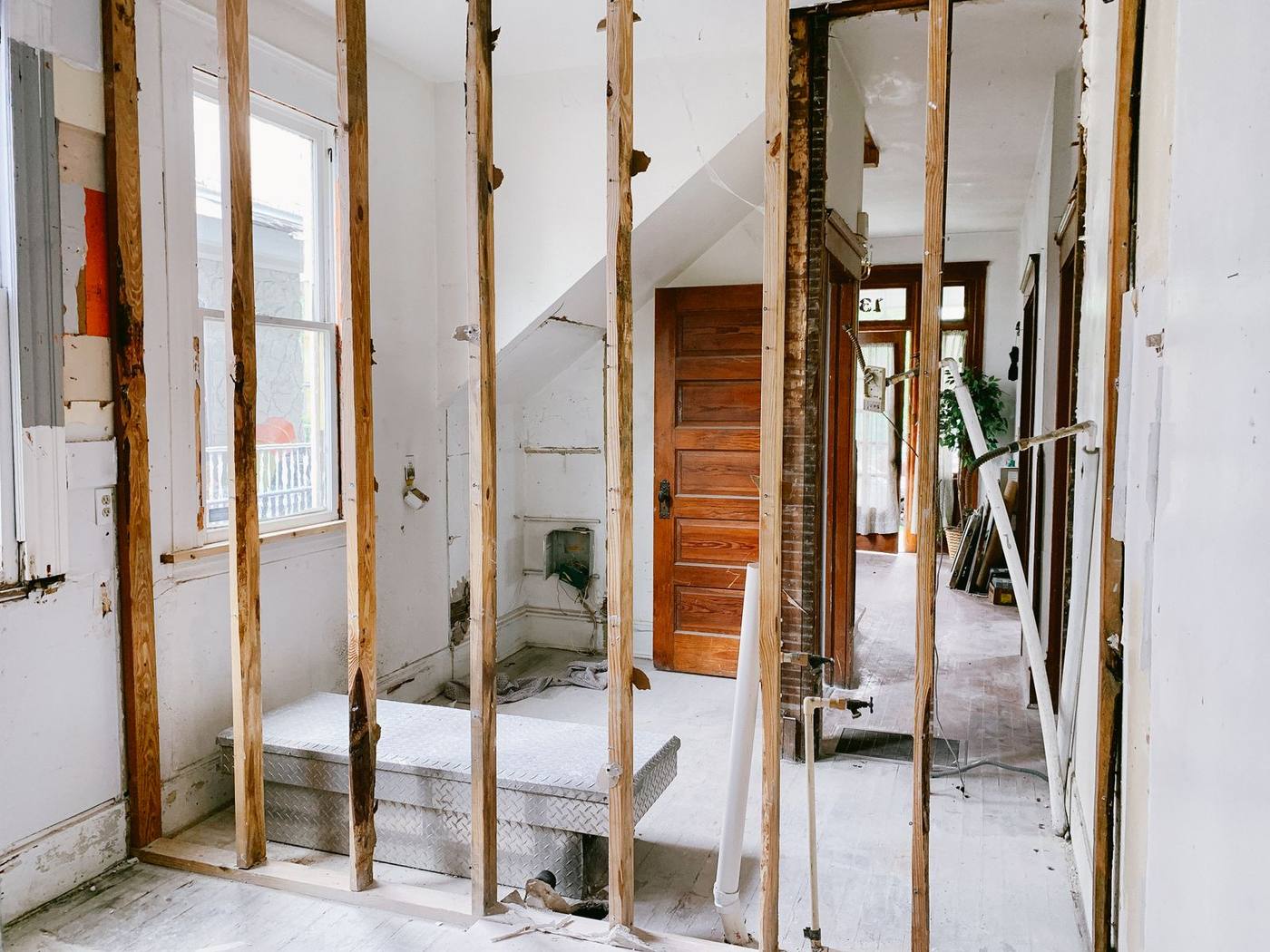 Exposed timber wall studs in a home under renovation, with a wooden door and hallway beyond