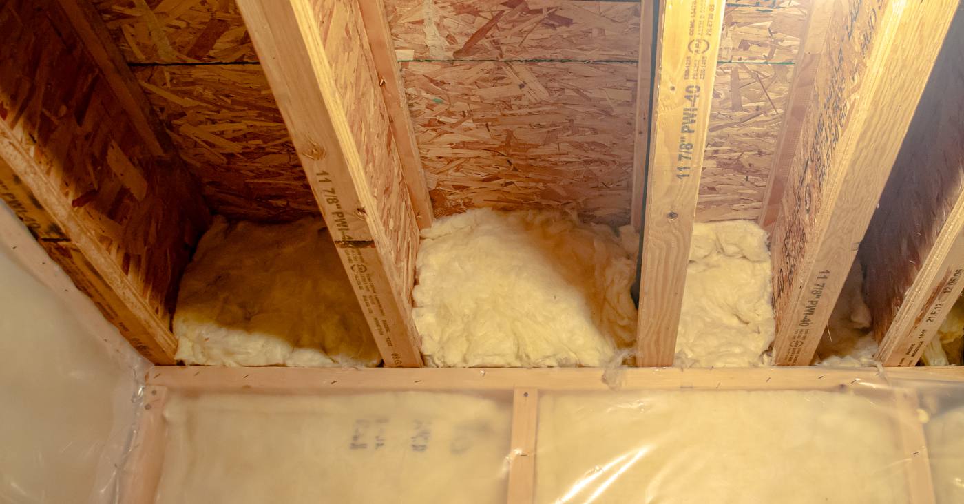 An engineered timber I-joist in a basement ceiling, with insulation between the joists
