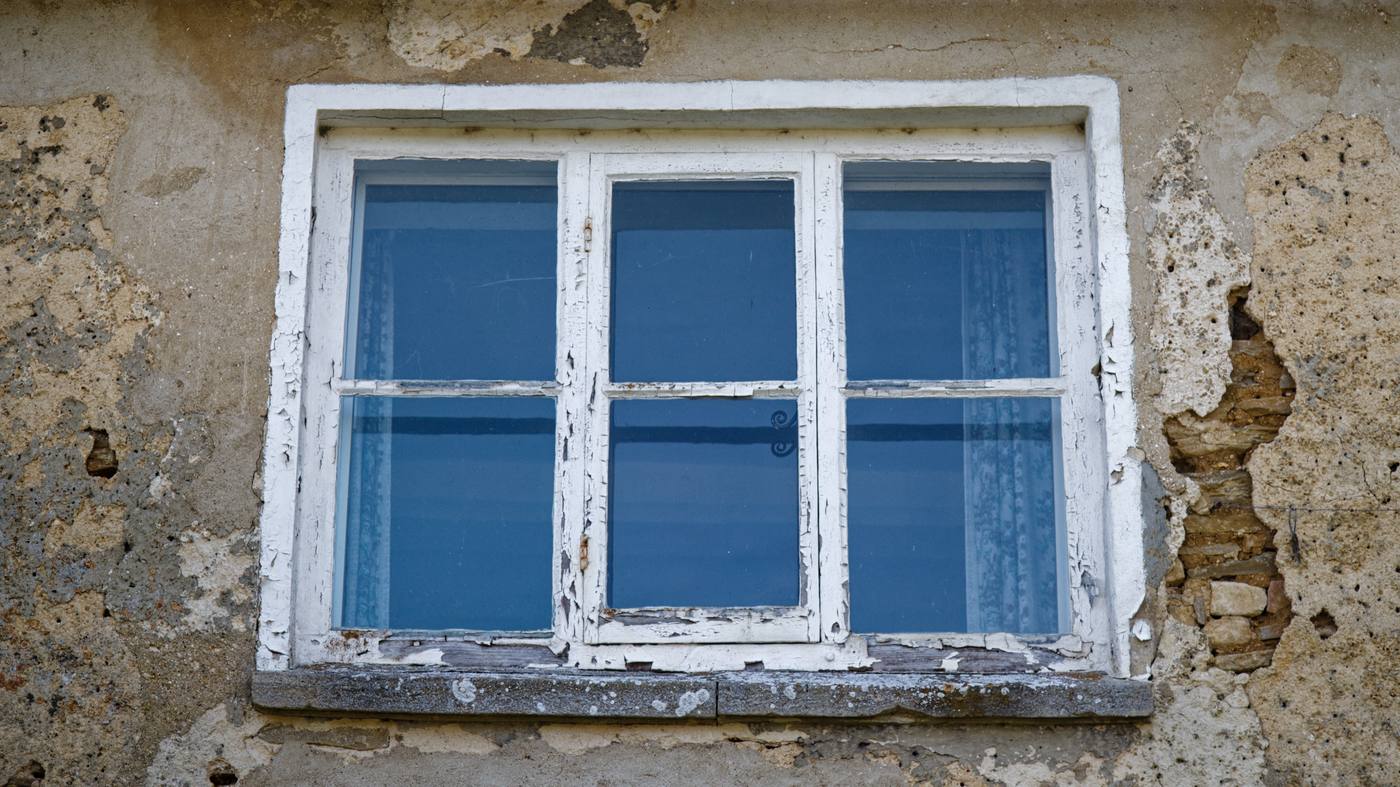 A dilapidated cottage upper window in a stone wall at Kencot