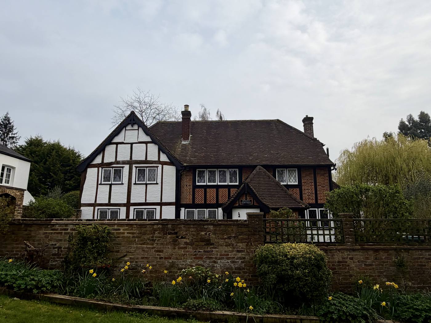 Pound Cottage, a white timber-framed house with dark timber framing behind a brick garden wall