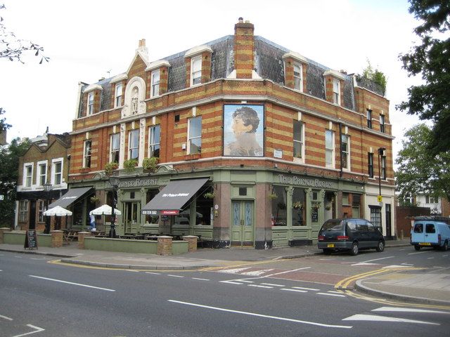 A Victorian building in Herne Hill, London, with a steep mansard roof, slate fish-scale tiles and striped brick dormer windows