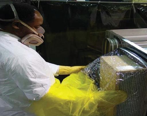 A worker removing a dirty air filter from a ventilation unit into a plastic bag