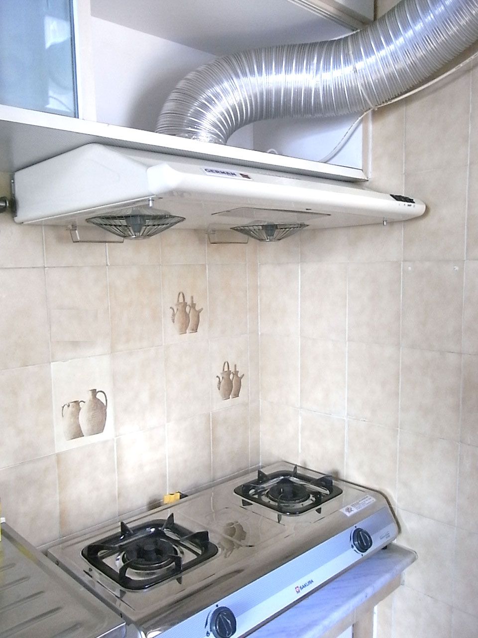 A wall-mounted extractor hood above a gas cooker in a home kitchen