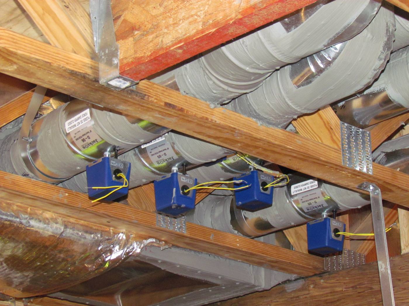 Ductwork and motorised dampers installed in the ceiling joists of a test house basement