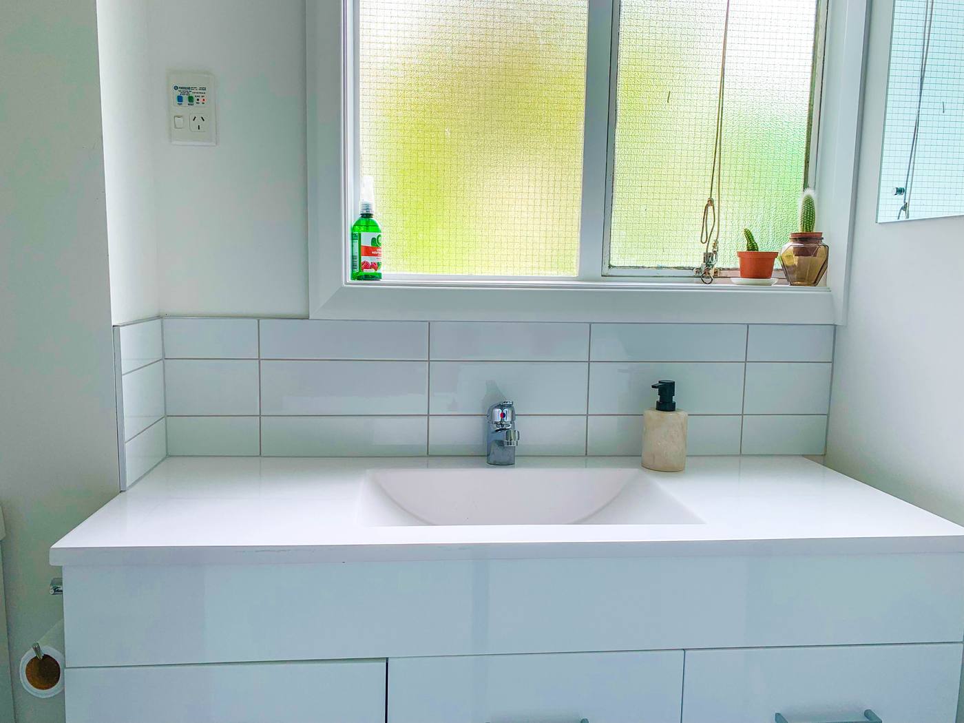 Tiled splashback in a bathroom — large tiles and fewer grout lines where steam and splashes land daily