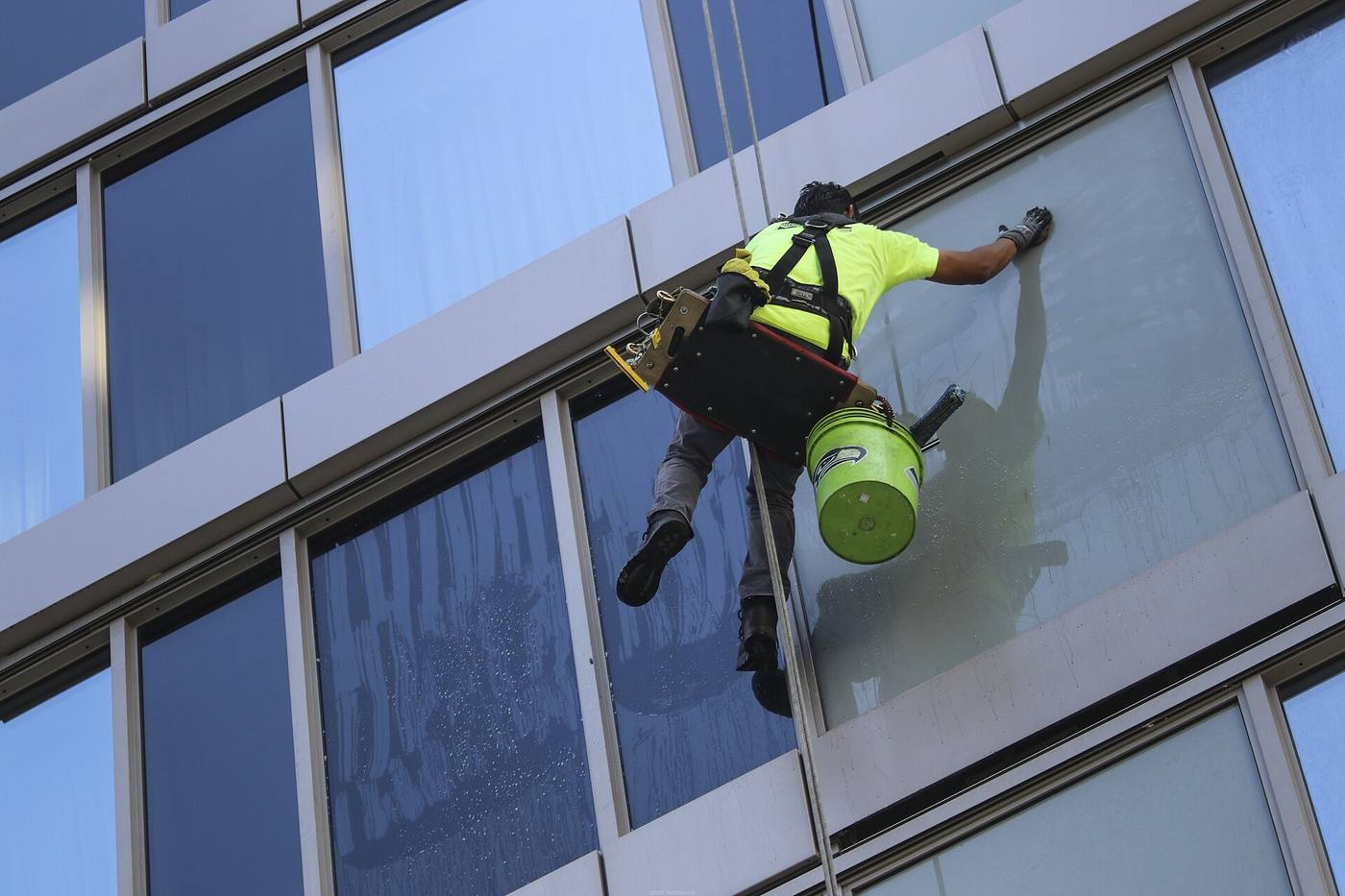 Workers cleaning the windows of a skyscraper facade from suspended platforms at height