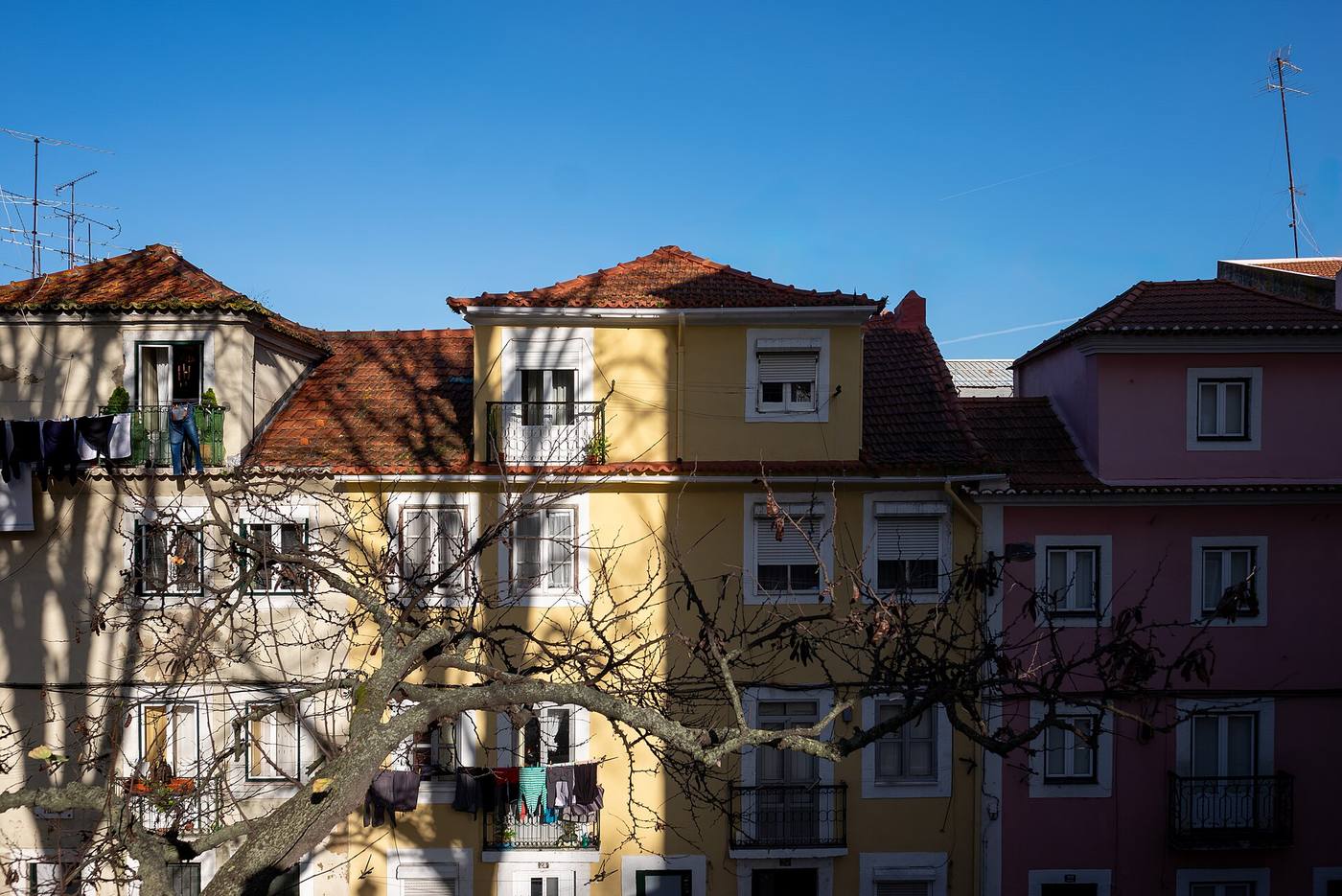 A Lisbon street building half in shadow and half in sunshine, showing uneven solar exposure across a facade