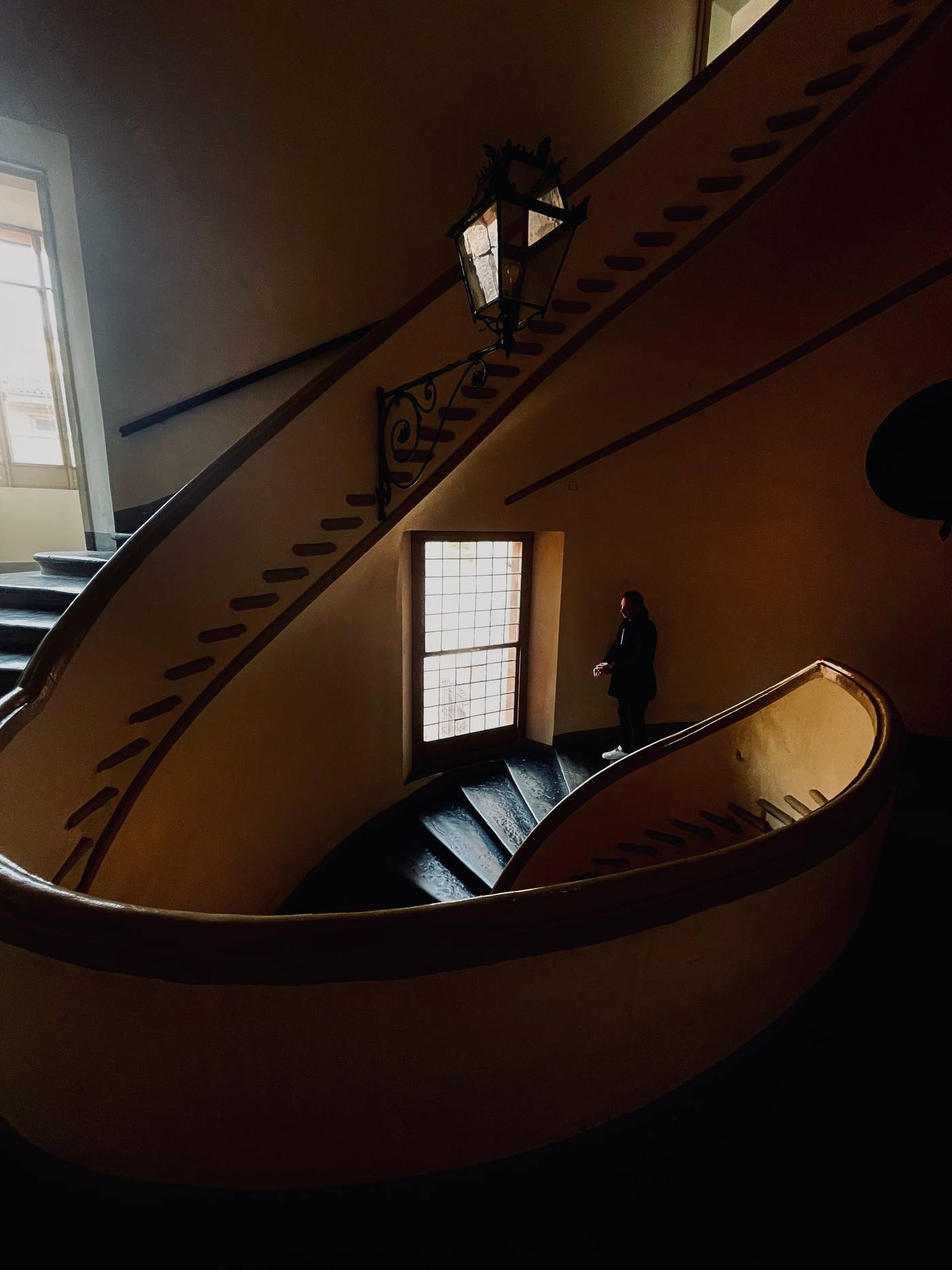 A person on a beautifully designed curved staircase indoors in Bologna, Italy