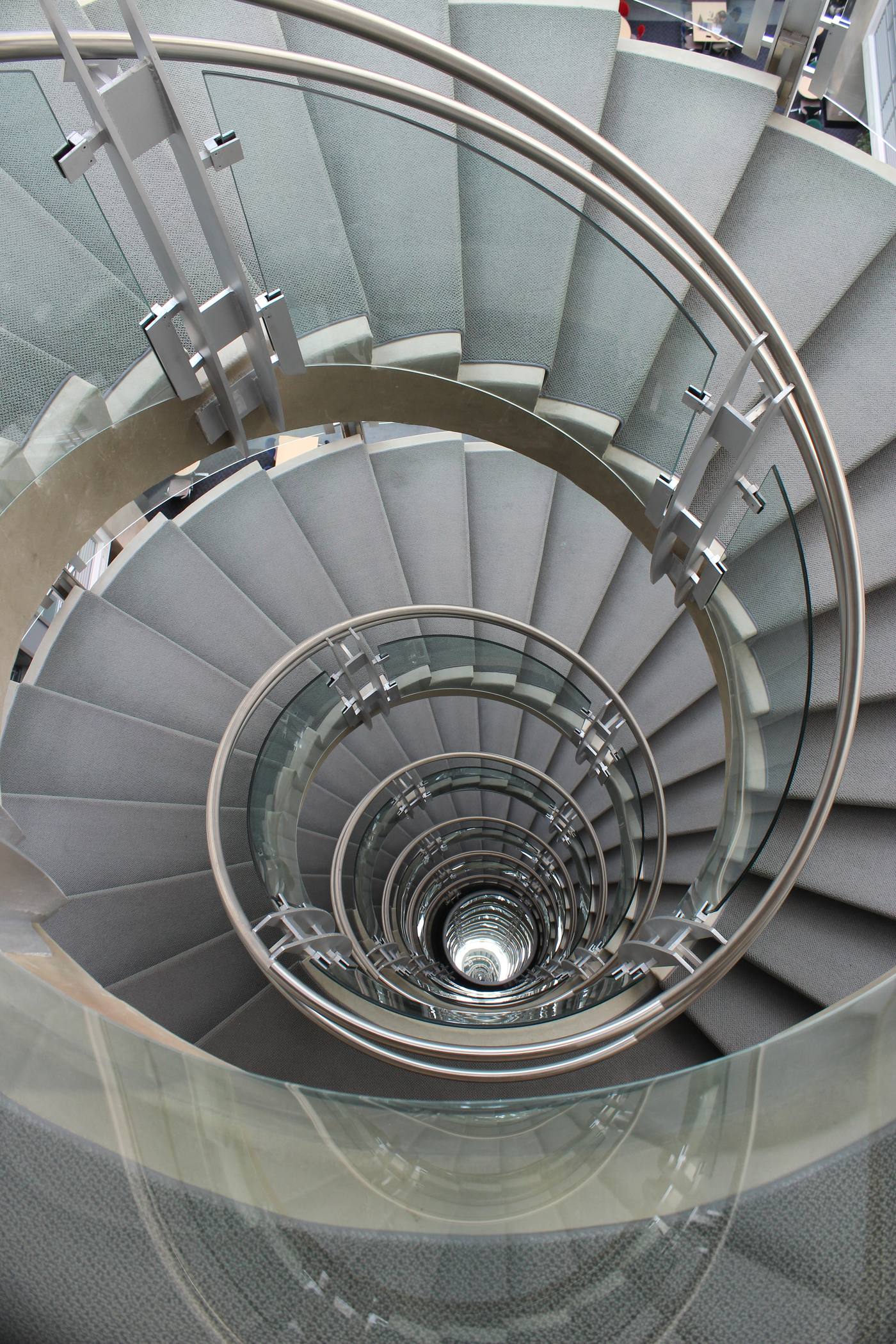 A tall spiral staircase of steel, mirror and glass rising through a multi-storey atrium at the Keck Center