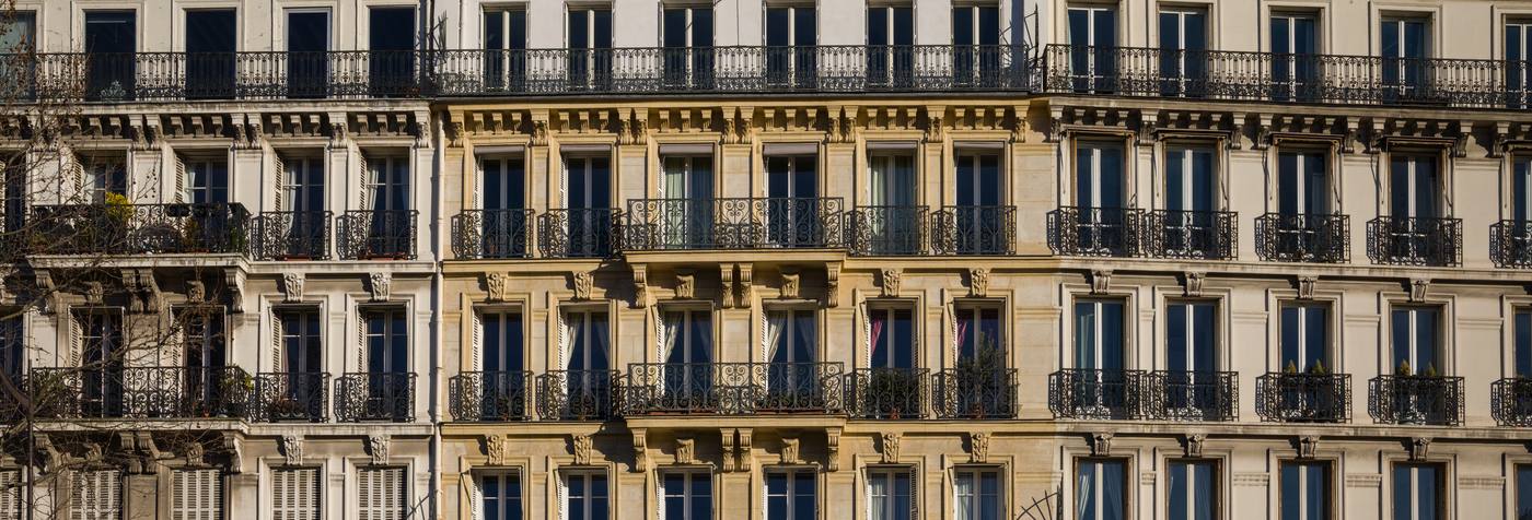 Limestone Haussmann residential facades with wrought-iron balconies on a Paris street