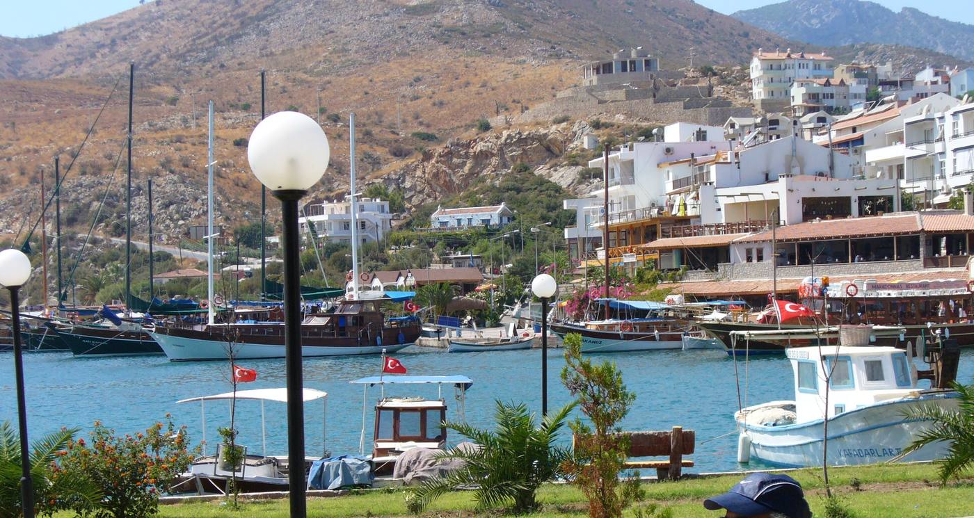 Yachts moored in Datça's harbour, with waterfront buildings climbing a dry hillside