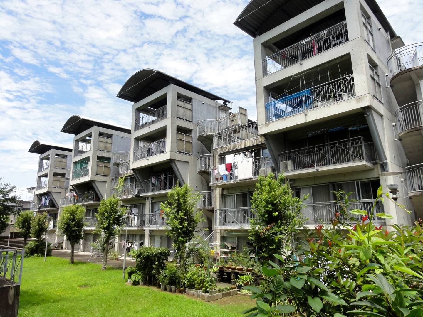 Hotakubo housing in Kumamoto, Japan — concrete housing blocks with curved roofs around a planted courtyard