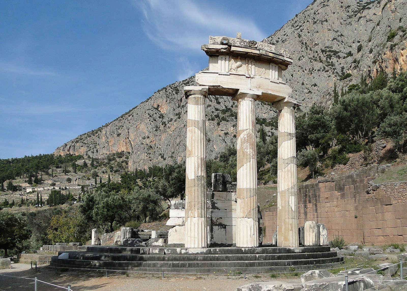 The circular Tholos of Athena Pronaia at Delphi, three columns standing against the mountain