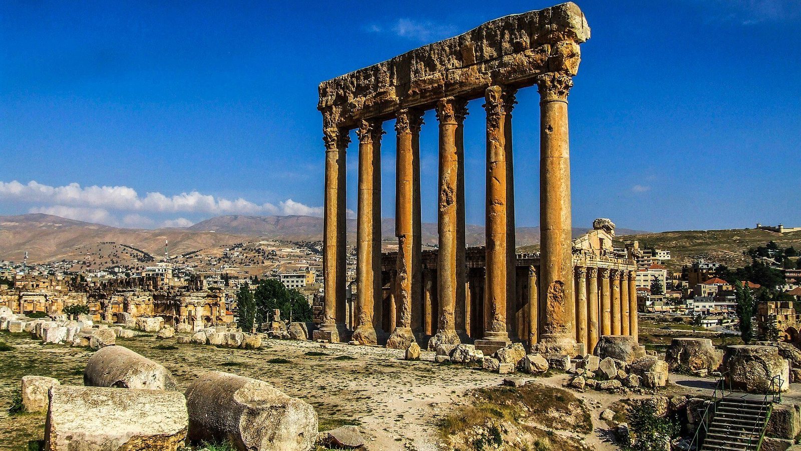The six colossal standing columns of the Temple of Jupiter at Baalbek, with the smaller Temple of Bacchus and the modern town spread out behind