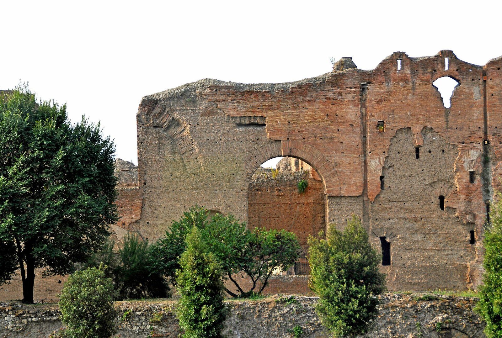 The ruined brick walls of the Baths of Caracalla in Rome: a long range of broken walls and great arched openings standing open to the sky