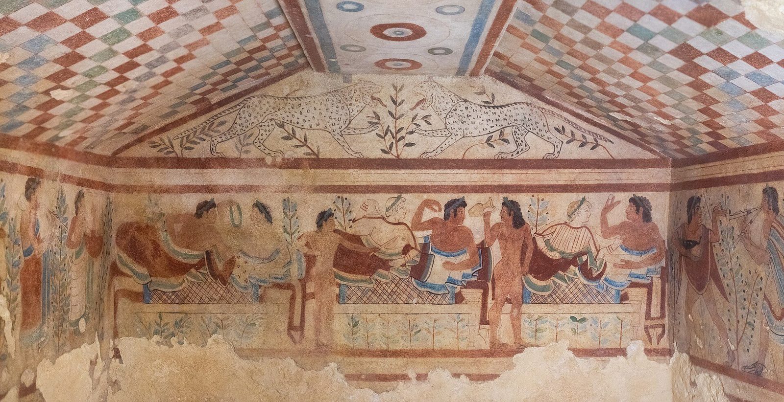 The painted banquet frieze of the Tomb of the Leopards at Tarquinia: reclining diners, dancers and musicians beneath a chequered pitched ceiling