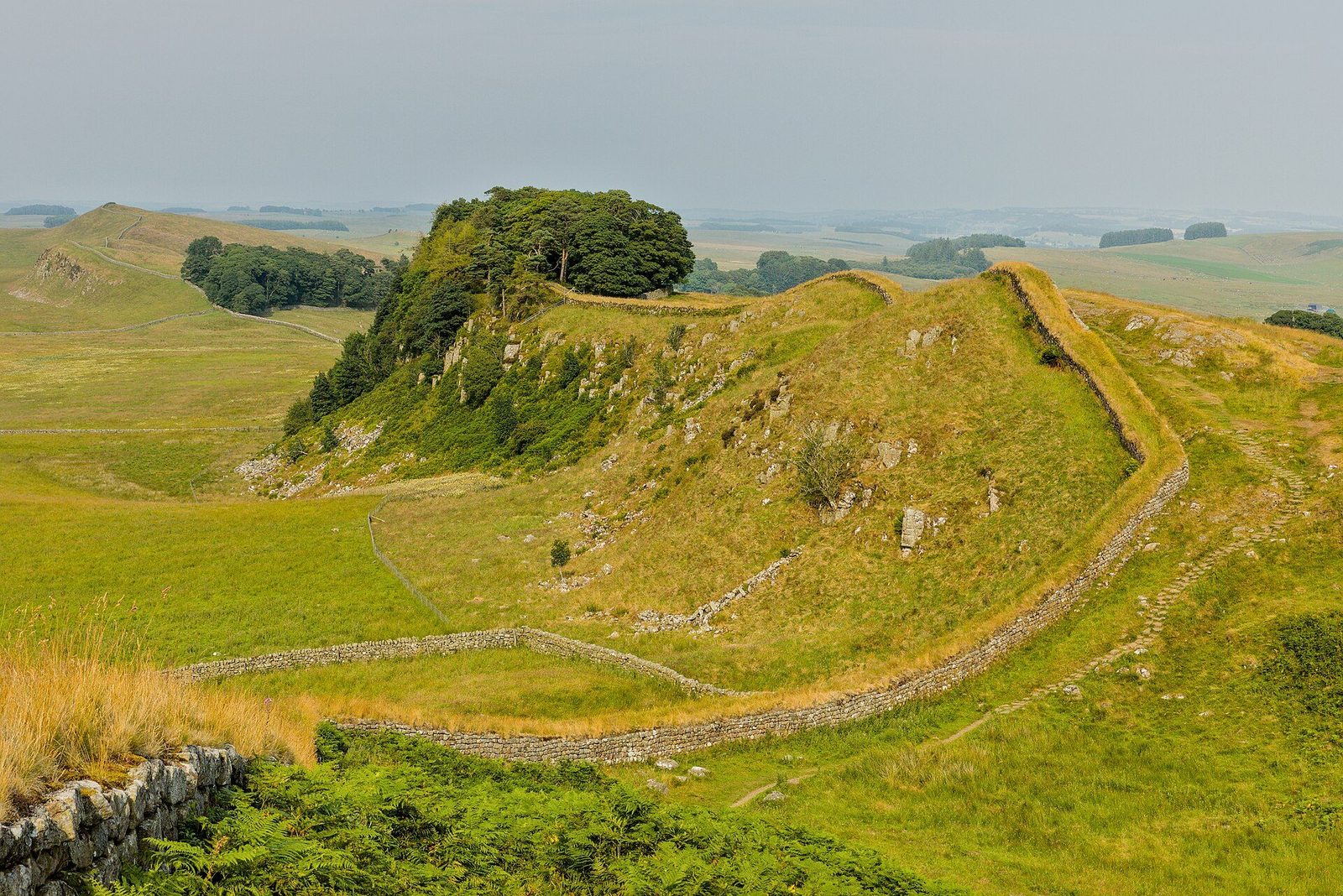 Hadrian's Wall snaking along the top of the green Housesteads crags in Northumberland, following the ridge into the distance