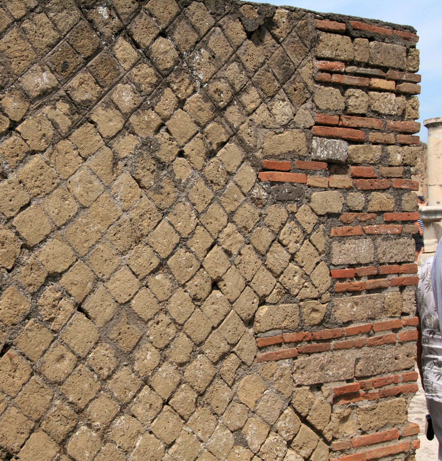 A wall faced in opus reticulatum at Pompeii: small square stones set diagonally in a diamond-net pattern, edged and repaired with bands of brick