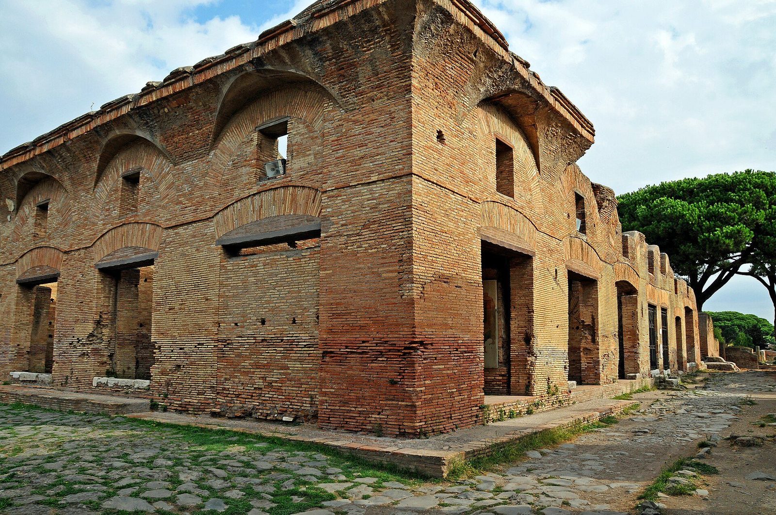 The Casa di Diana at Ostia Antica: a well-preserved brick insula apartment block with arched windows, fronting a cobbled street