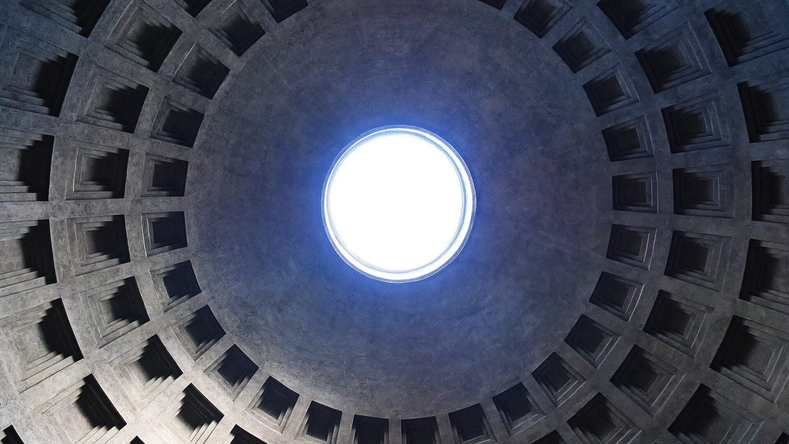 The Pantheon's coffered concrete dome seen from inside: rings of coffers narrowing toward the open oculus at the crown