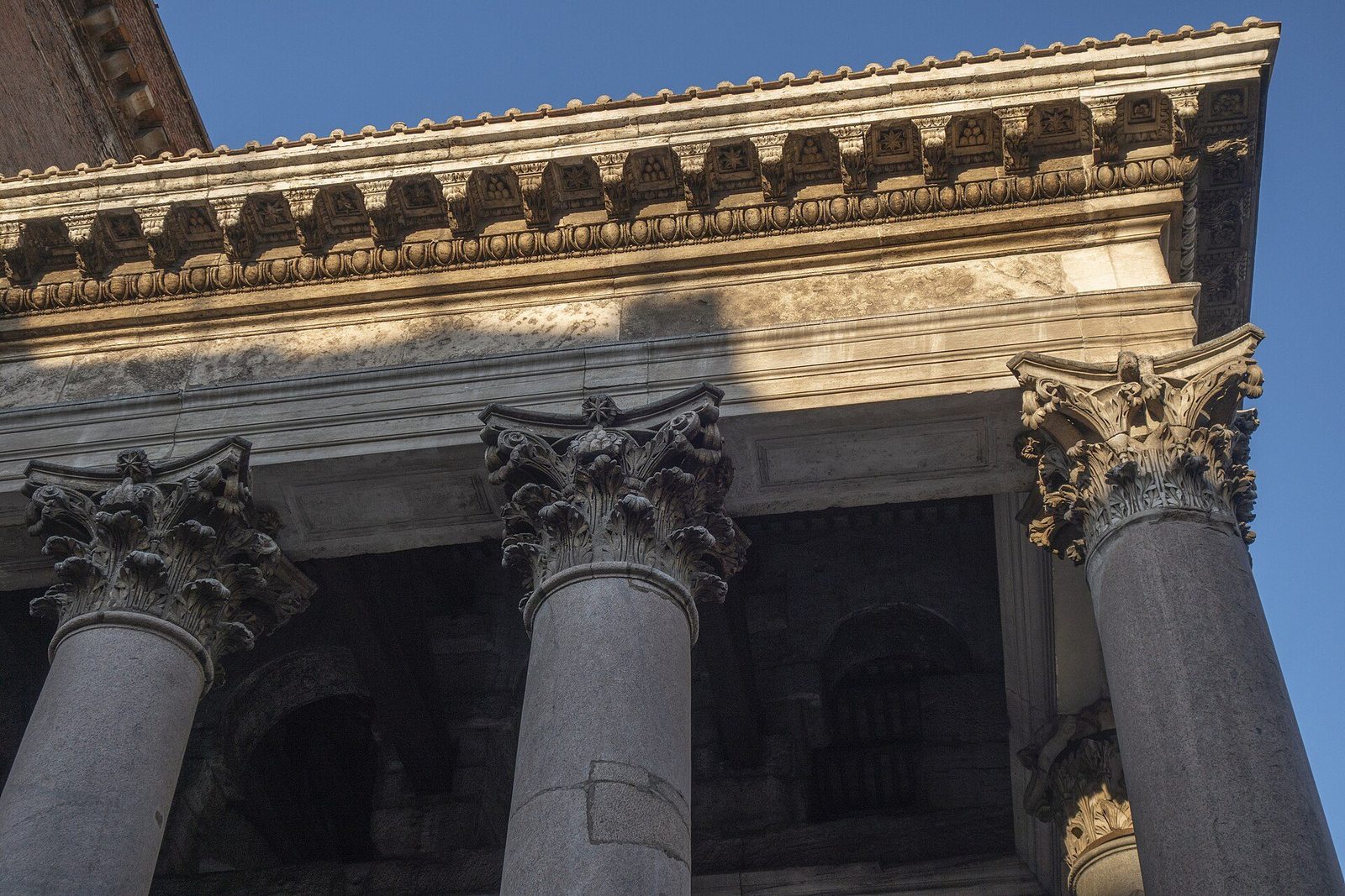 The Pantheon's portico close up: monolithic grey granite columns with Corinthian capitals carrying the deep entablature