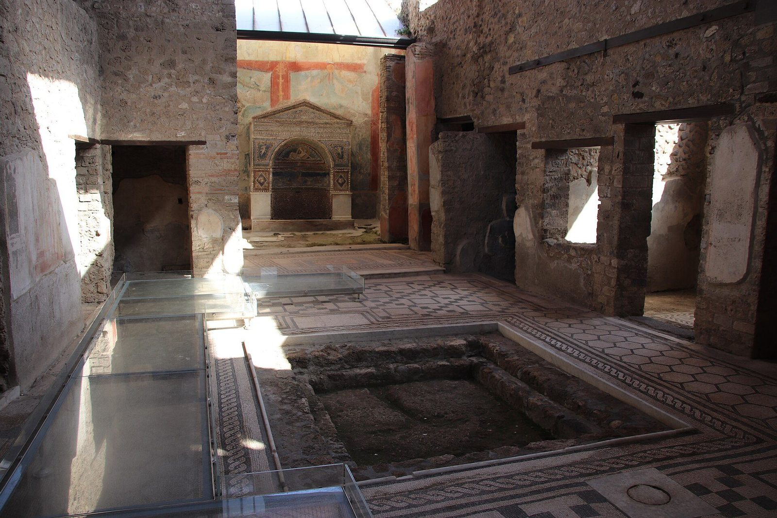 The atrium of the House of the Bear at Pompeii: the sunken impluvium in the mosaic floor, with the household shrine in the tablinum beyond