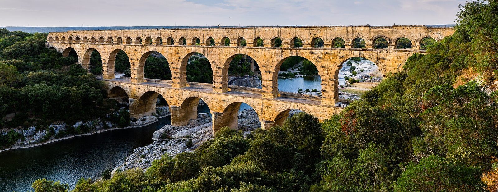The Pont du Gard in southern France: three tiers of golden stone arches carrying the aqueduct channel across the wooded Gardon valley