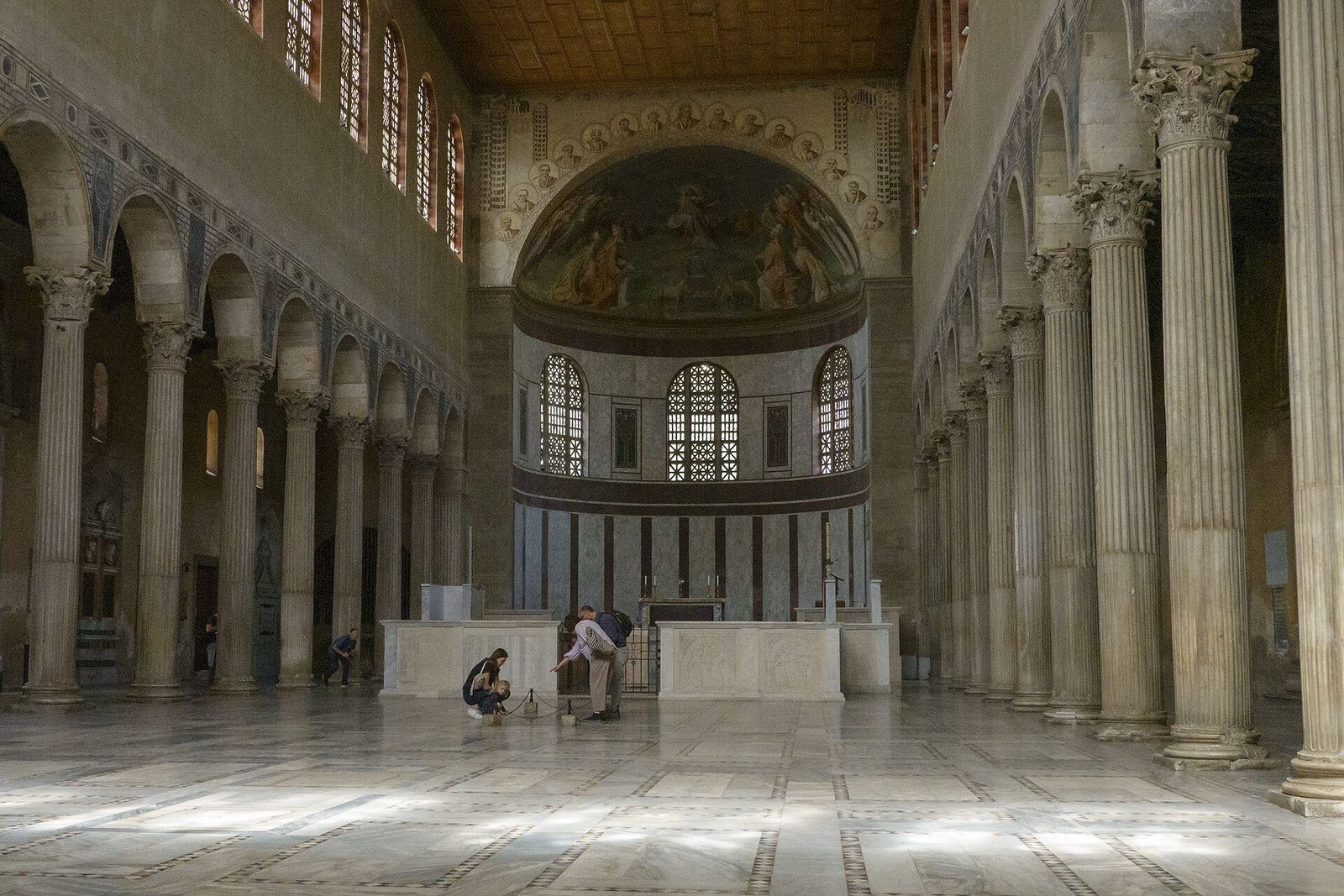 The nave of Santa Sabina in Rome: marble colonnades and high clerestory windows lighting the long, plain basilica toward its apse