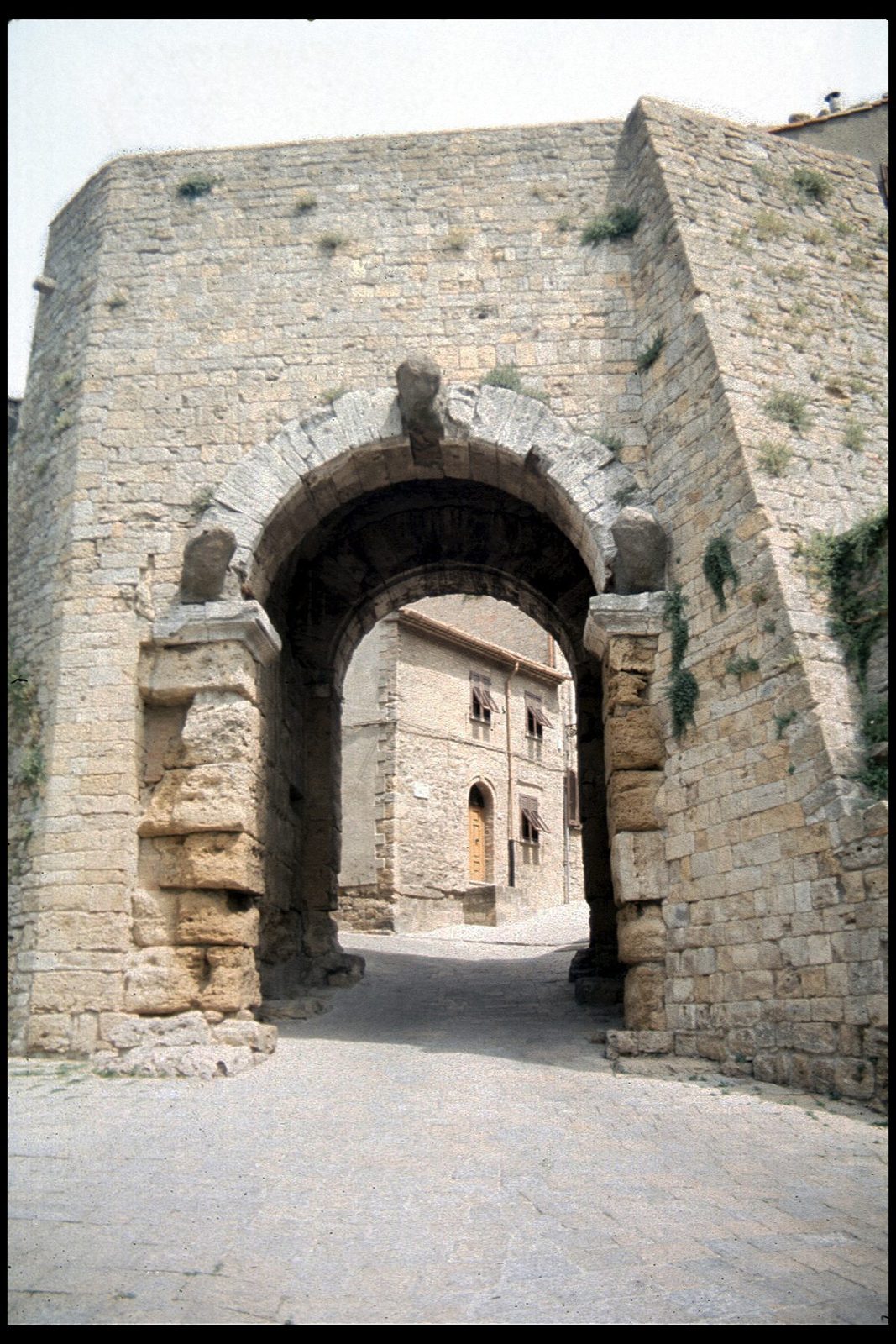 The Porta all'Arco at Volterra: the Etruscan city gate of massive stone blocks, its arch decorated with three weathered carved heads