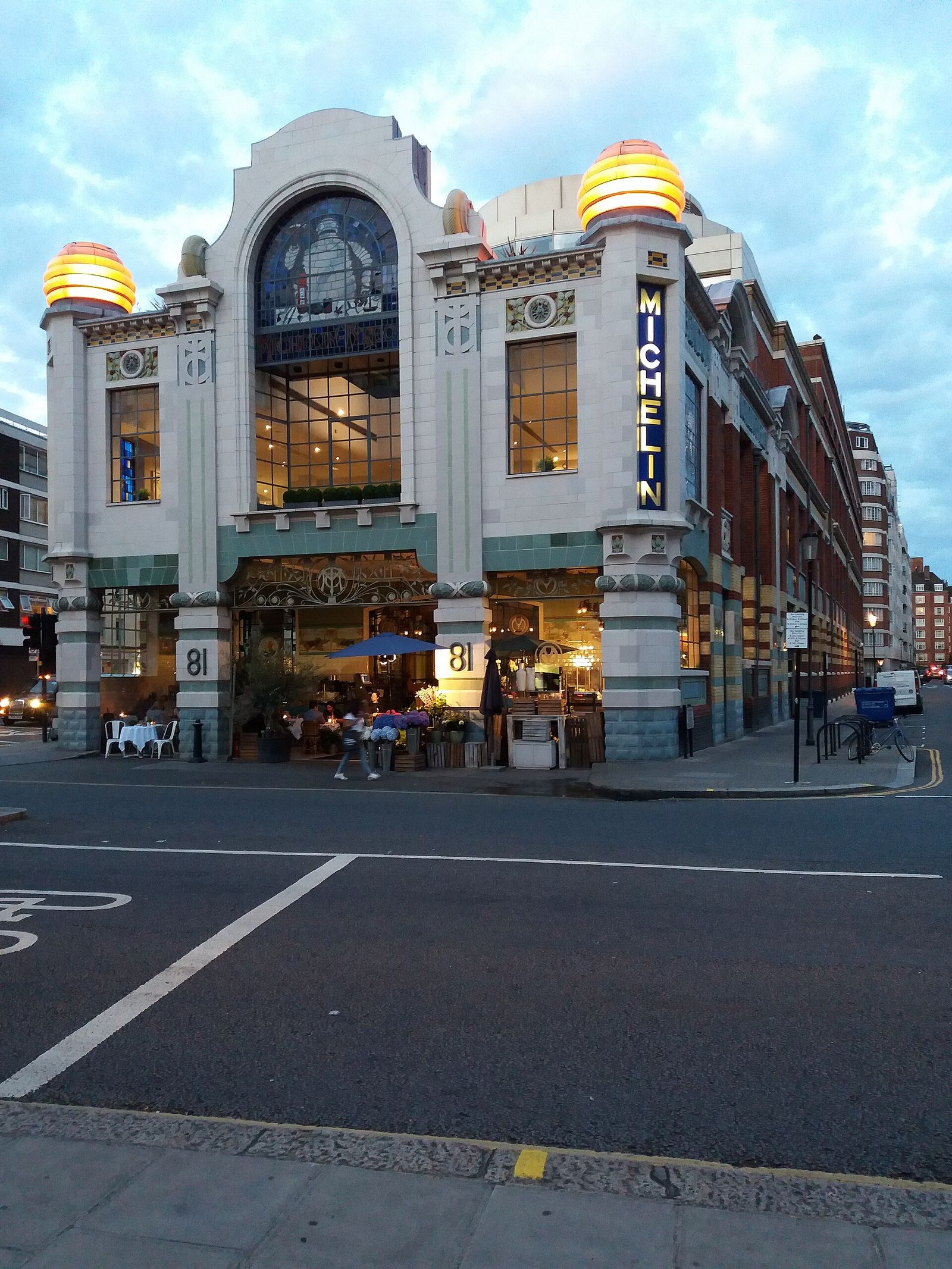 Michelin House on Fulham Road in London at dusk, its stained-glass windows and tyre-stack lights glowing