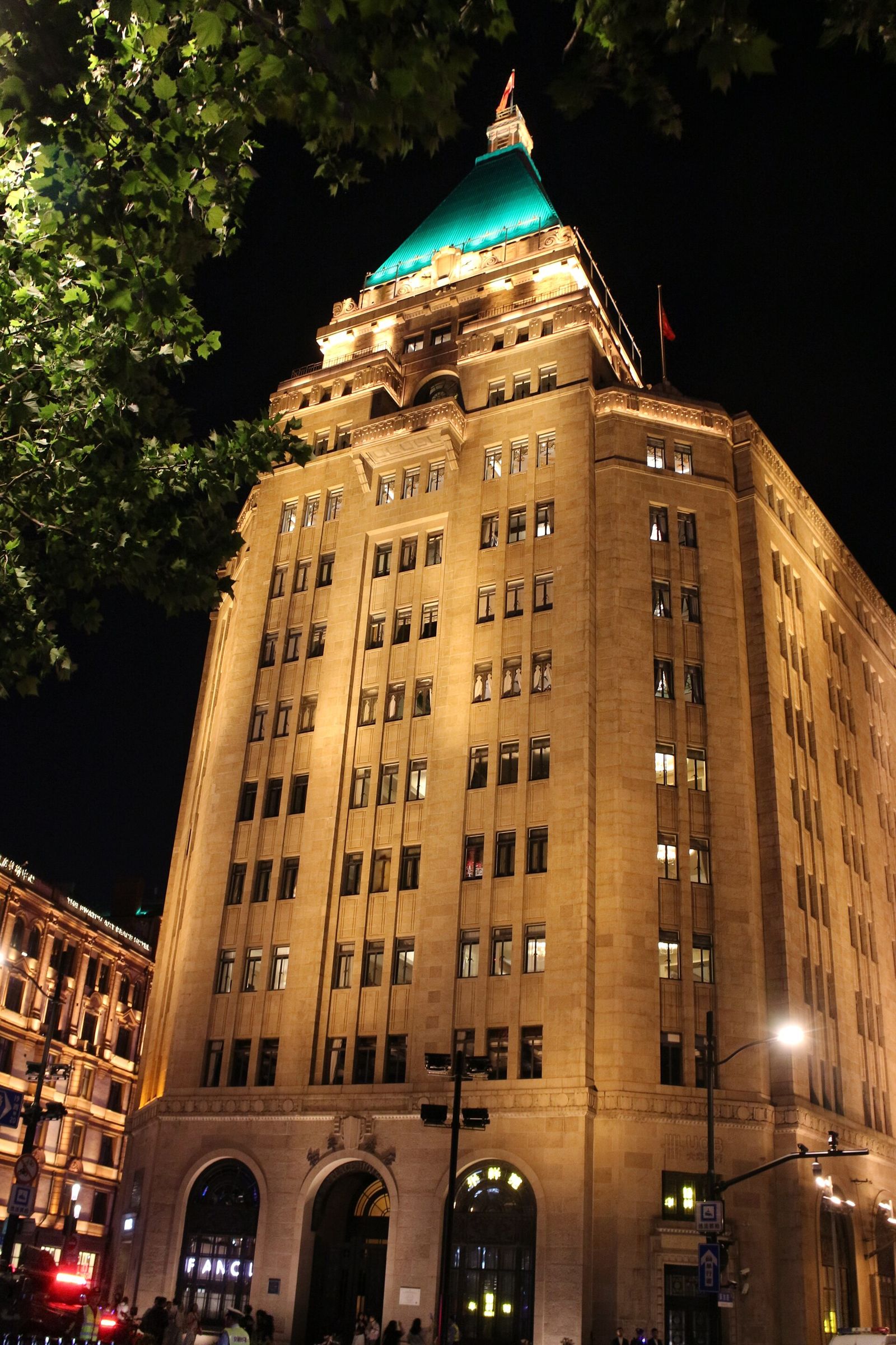 The Peace Hotel (Sassoon House) on the Bund in Shanghai at night, its green pyramid roof lit