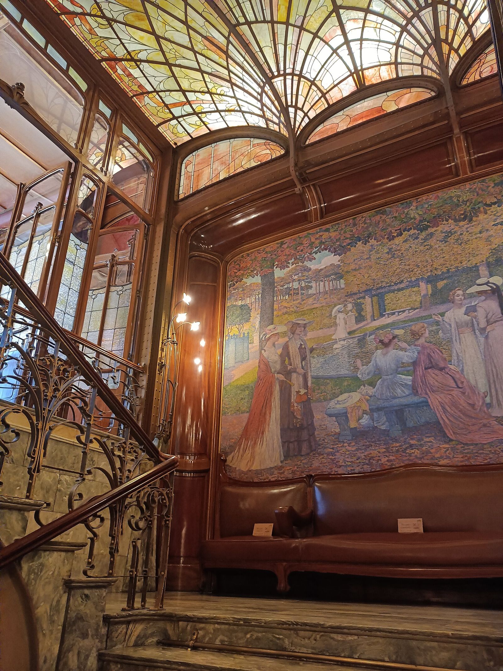 The main stair of the Hôtel Solvay in Brussels, its iron railing uncurling beside the muralled wall