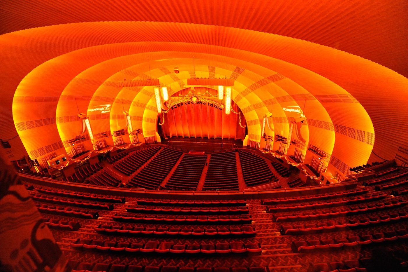The auditorium of Radio City Music Hall, its concentric golden proscenium arcs glowing red-orange