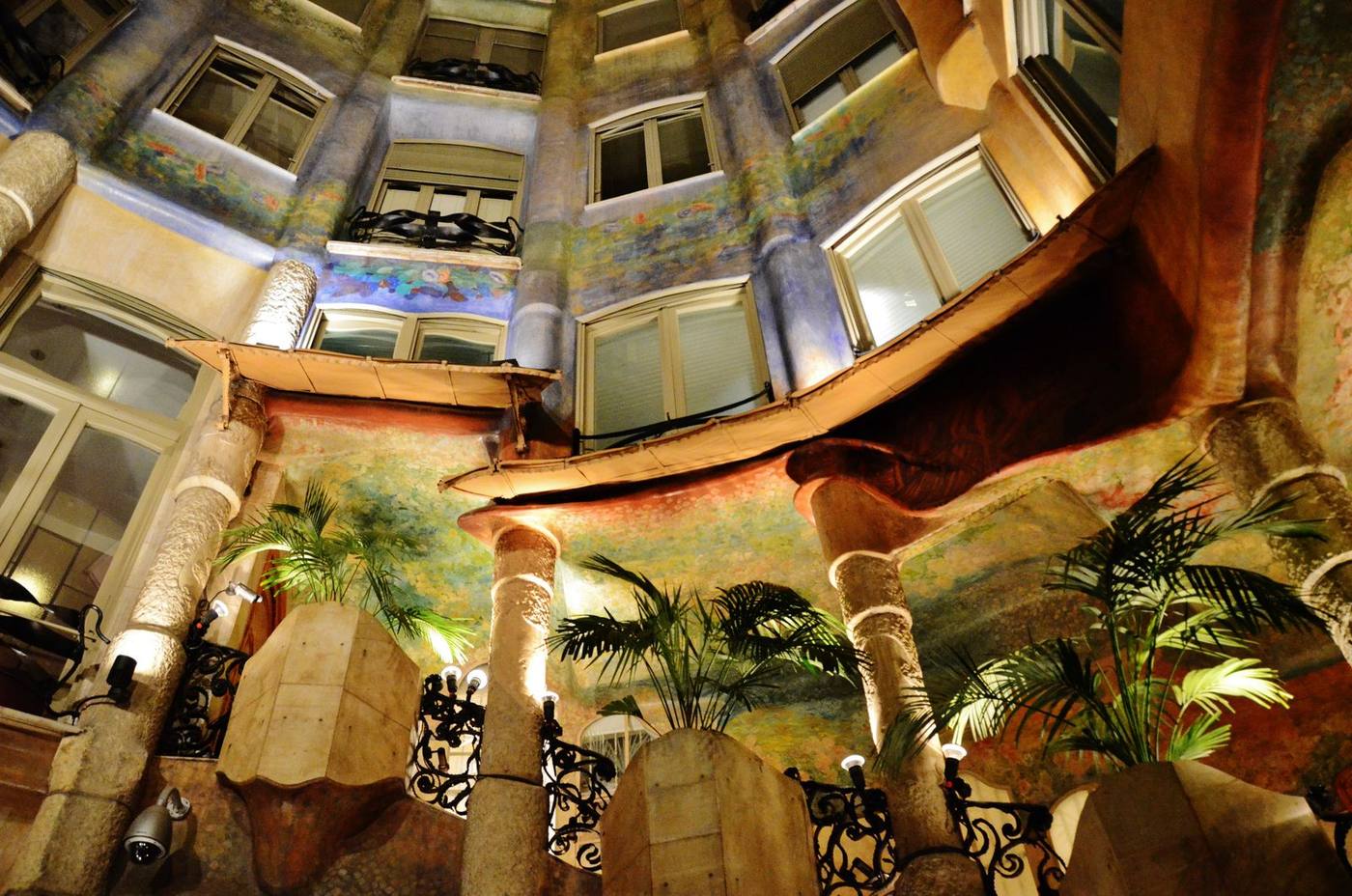 The painted inner courtyard of Casa Milà in Barcelona, looking up past its undulating balconies and floral murals