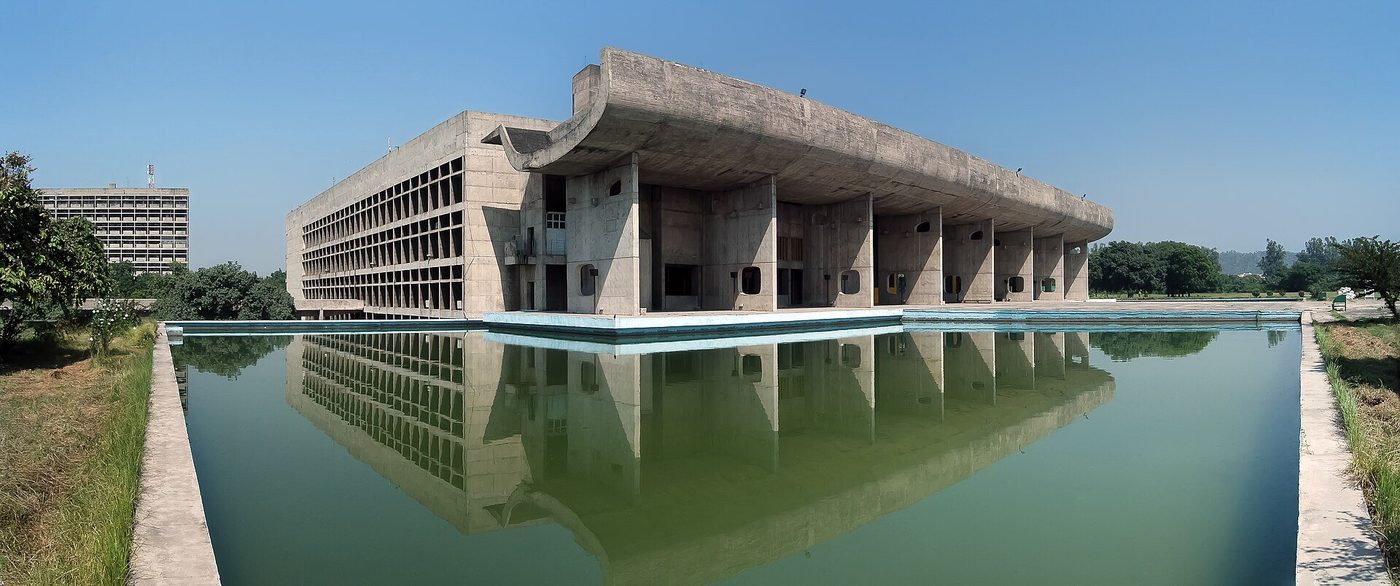 The Palace of Assembly at Chandigarh across its reflecting pool — portico, curved chamber shell and tower